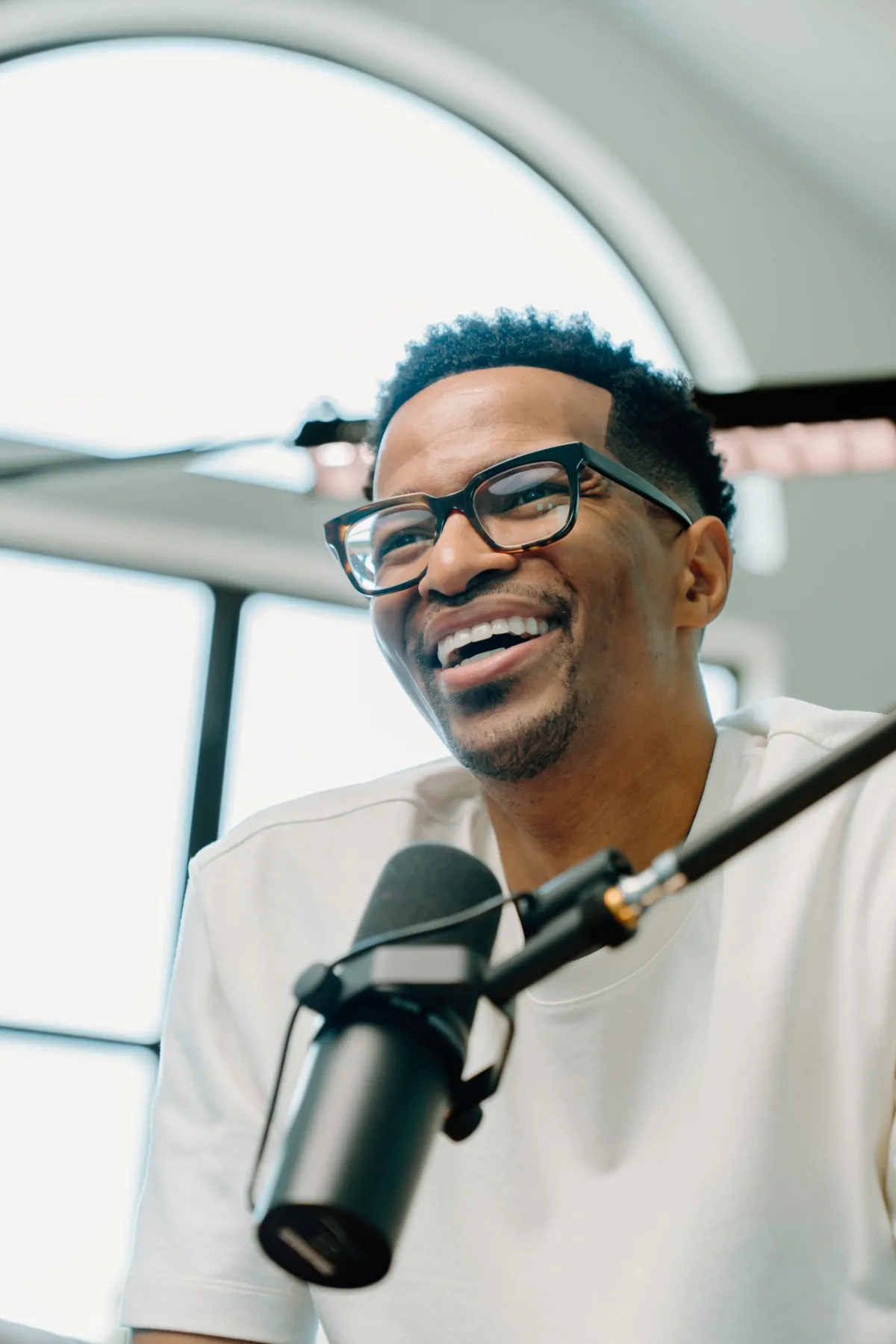 Laughing behind the mic in a podcast studio